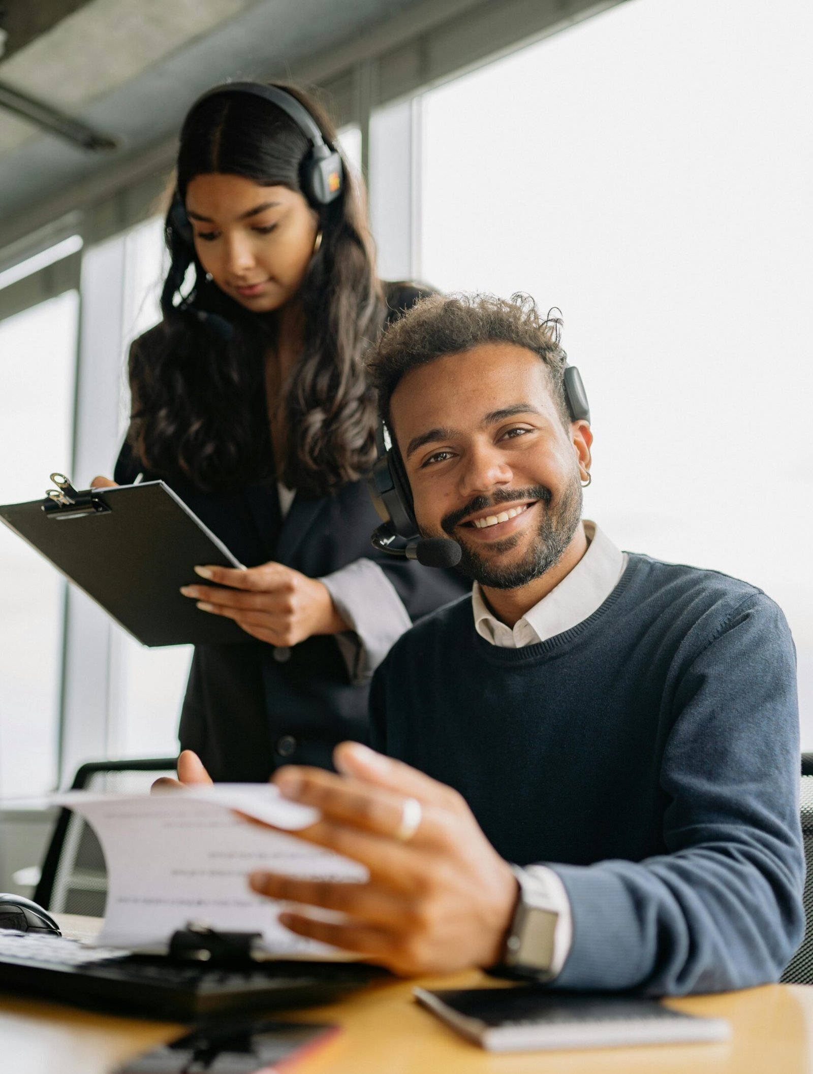 Two call center agents collaborating in a modern office environment.